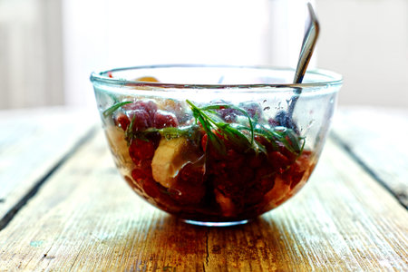 salad of fresh bananas, raspberries, estragon and honey in transparent plate on wooden background. Selective focusの写真素材