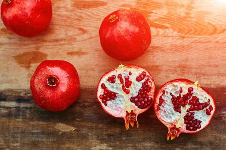 ripe cracked raw pomegranates on a dark wooden backgroundの写真素材