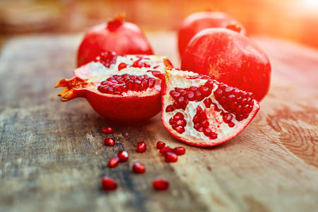 ripe cracked raw pomegranates on a dark wooden backgroundの写真素材
