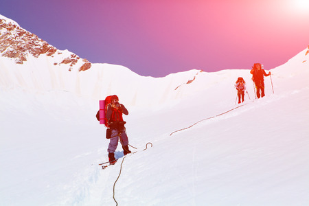 hikers at the top of a pass with backpacks meeting the sunrise in the mountainsの写真素材