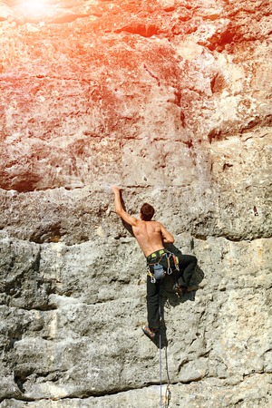 Young man climbs on a rocky wallの写真素材