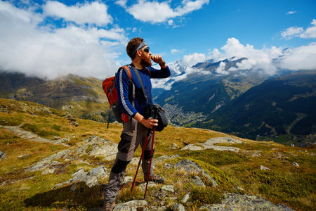 hiker at the top of a pass with backpack enjoy sunny day in Alps. Switzerland, Trek near Matterhorn...