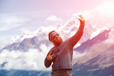 hiker at the top of a pass with backpack making selfie against  snow capped mountains in Alps. Switzerland, Trek near Matterhorn mount.の写真素材