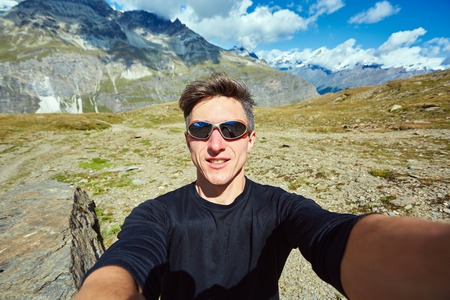 hiker  at the top of a pass  making selfie against  snow capped mountains in Alps. Switzerland, Trek near Matterhorn mount.の写真素材