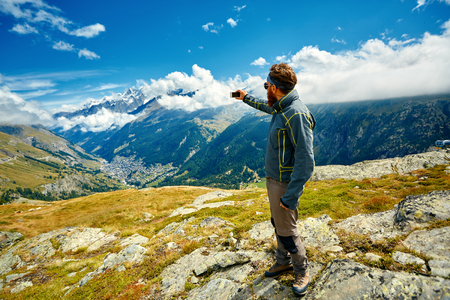 hiker  at the top of a pass  making selfie against  snow capped mountains in Alps. Switzerland, Trek near Matterhorn mount.の写真素材