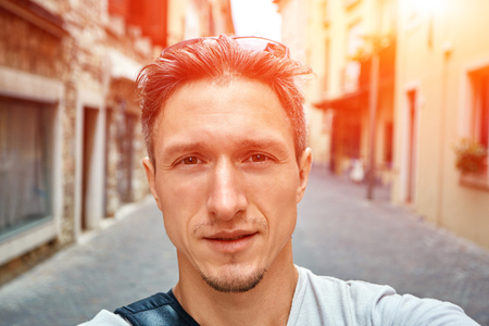young  man make selfie on the old italian town background. Man dressed in a white t-shirt and white sunglassesの写真素材