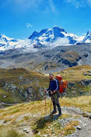 tired hiker with backpack on the trail in the Apls mountains. Trek near Matterhorn mountの写真素材
