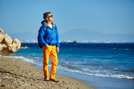 traveler with backpack standing on the beach against the sea and blue sky at early morningの写真素材