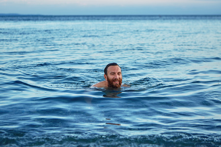smiling man swims in the sea at dawn.の写真素材