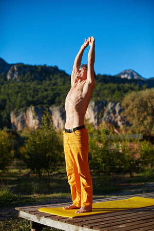 young man doing yoga in the early morning on the garden terrace of the houseの写真素材