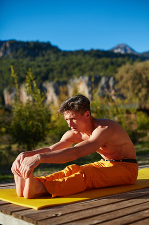young man doing yoga in the early morning on the garden terrace of the houseの写真素材
