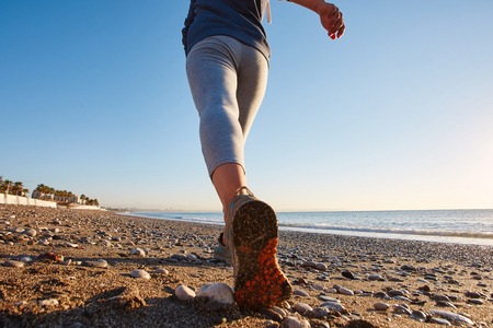 Young lady running on the beach at sunrise. shoes closeupの写真素材