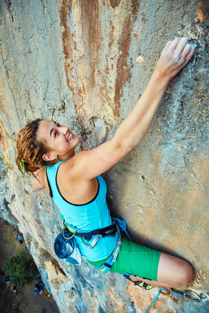 female rock climber climbs on a rocky wallの写真素材
