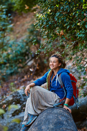 Active healthy woman hiking in beautiful forest. Portrait of happy smiling young woman resting of forest clearing during hike holidays.の写真素材