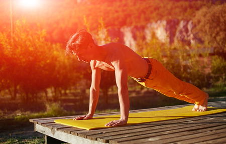 young man doing yoga in the early morning on the garden terrace of the houseの写真素材