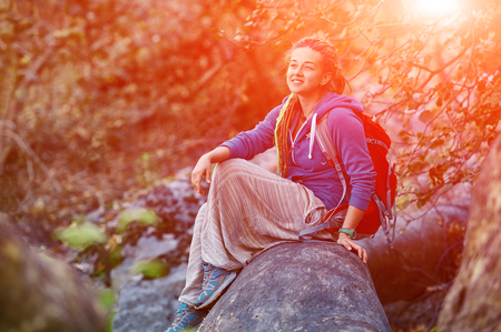 Active healthy woman hiking in beautiful forest. Portrait of happy smiling young woman resting of forest clearing during hike holidays.の写真素材