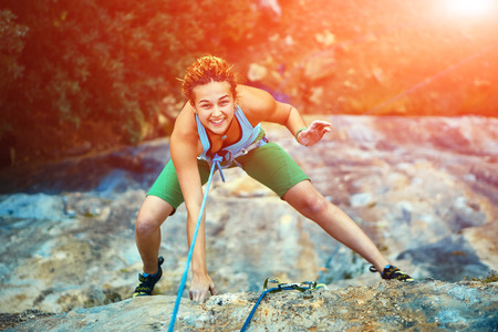 female rock climber climbs on a rocky wallの写真素材