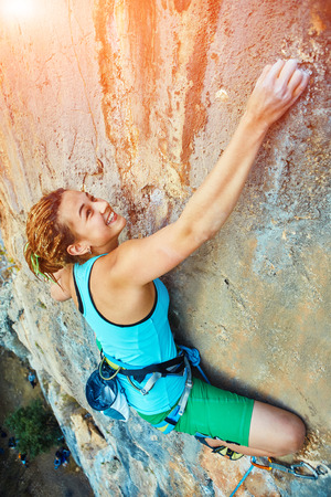 female rock climber climbs on a rocky wallの写真素材