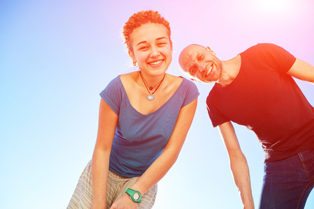happy attractive man and woman looks into the camera on the sunny beach over the blue sky. Focus on the womanの写真素材