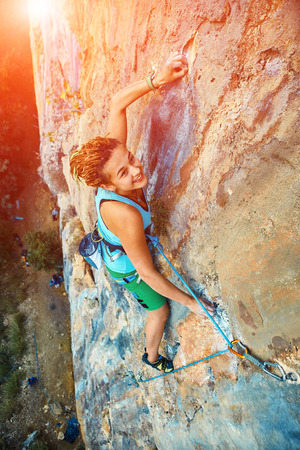female rock climber climbs on a rocky wallの写真素材