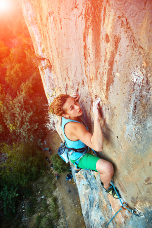 female rock climber climbs on a rocky wallの写真素材