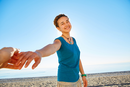 happy attractive  woman looks into the camera on the sunny beach over the blue skyの写真素材
