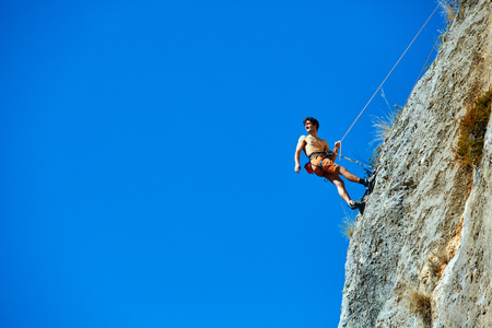 male rock climber climbs on a rocky wallの写真素材