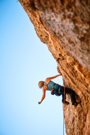 female rock climber climbs on a rocky wallの写真素材