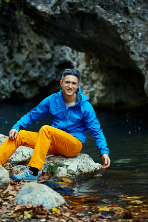 smiling hiker man sitting in the woods on the bank of the creek andの写真素材