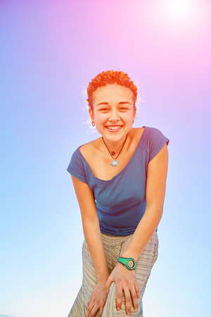 happy attractive  woman looks into the camera on the sunny beach over the blue skyの写真素材