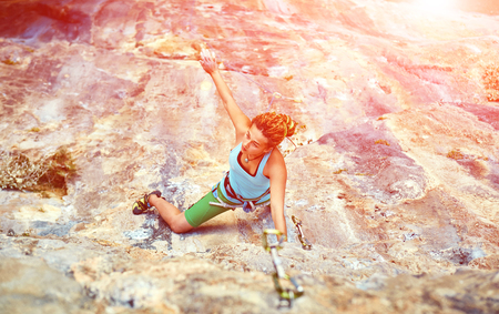 female rock climber climbs on a rocky wallの写真素材
