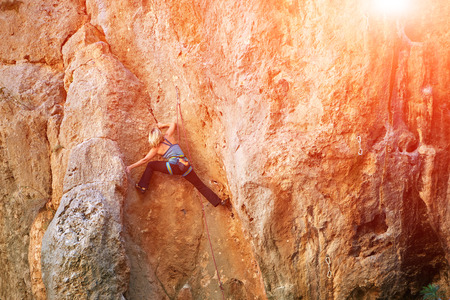 female rock climber climbs on a rocky wallの写真素材