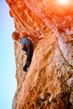 female rock climber climbs on a rocky wallの写真素材