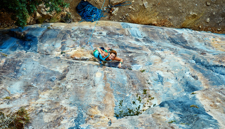 female rock climber climbs on a rocky wallの写真素材