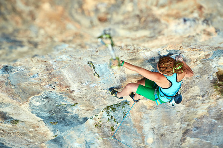 female rock climber climbs on a rocky wallの写真素材