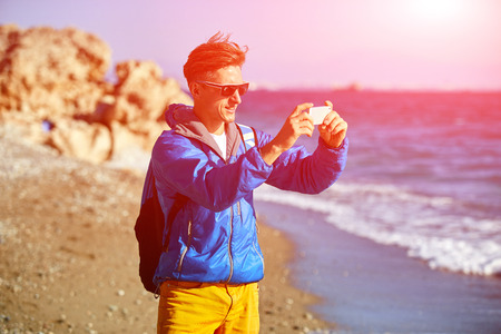 traveler with backpack making selfie against sea and blue sky at early morningの写真素材