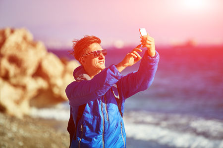 traveler with backpack making selfie against sea and blue sky at early morningの写真素材