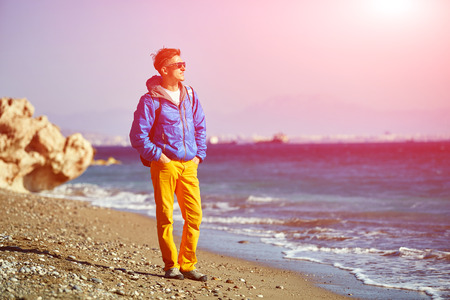traveler with backpack standing on the beach against the sea and blue sky at early morningの写真素材