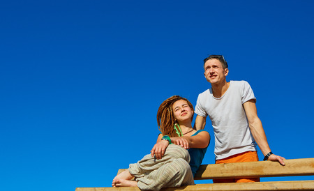 young happy couple  sitting on the bench over the blue skyの写真素材