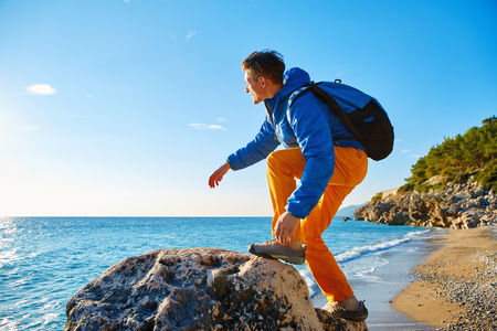 traveler with backpack standing on the cliff against sea and blue sky at early morningの写真素材