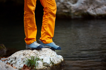 close-up legs  and feet of hiker man standing in the woods on the bank of the creekの写真素材