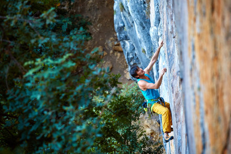 male rock climber climbs on a rocky wall