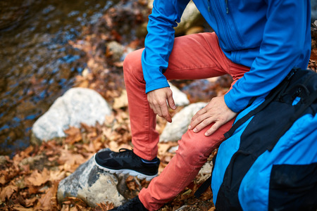 Active healthy man hiking in beautiful autumn forest. Portrait of happy smiling young man resting of forest clearing during hike holidays.の写真素材