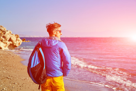 traveler with backpack standing on the beach against the sea and blue sky at early morningの写真素材