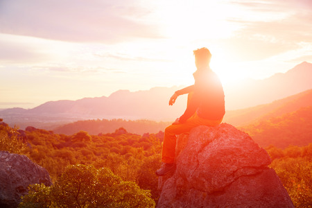 male traveler  standing on the cliff against mountains and cloudy  sky at early morningの写真素材