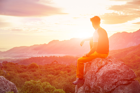 male traveler  standing on the cliff against mountains and cloudy  sky at early morningの写真素材