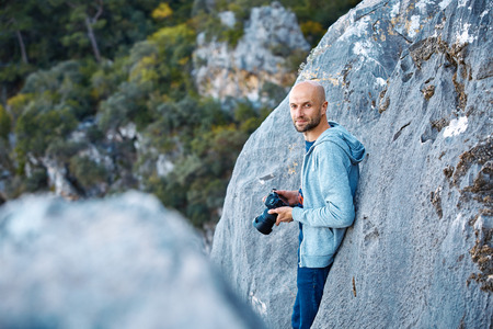 male photographer standing on the cliff  holds camera in his handsの写真素材