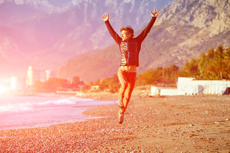 young man running on the beach and jumping at early morningの写真素材