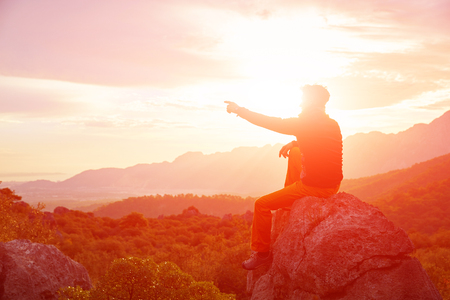 male traveler  standing on the cliff against mountains and cloudy  sky at early morningの写真素材