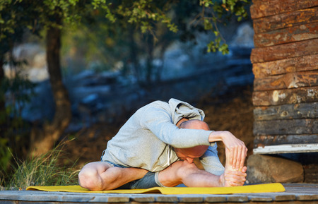 young man doing yoga in the early morning on the garden terrace of the houseの写真素材